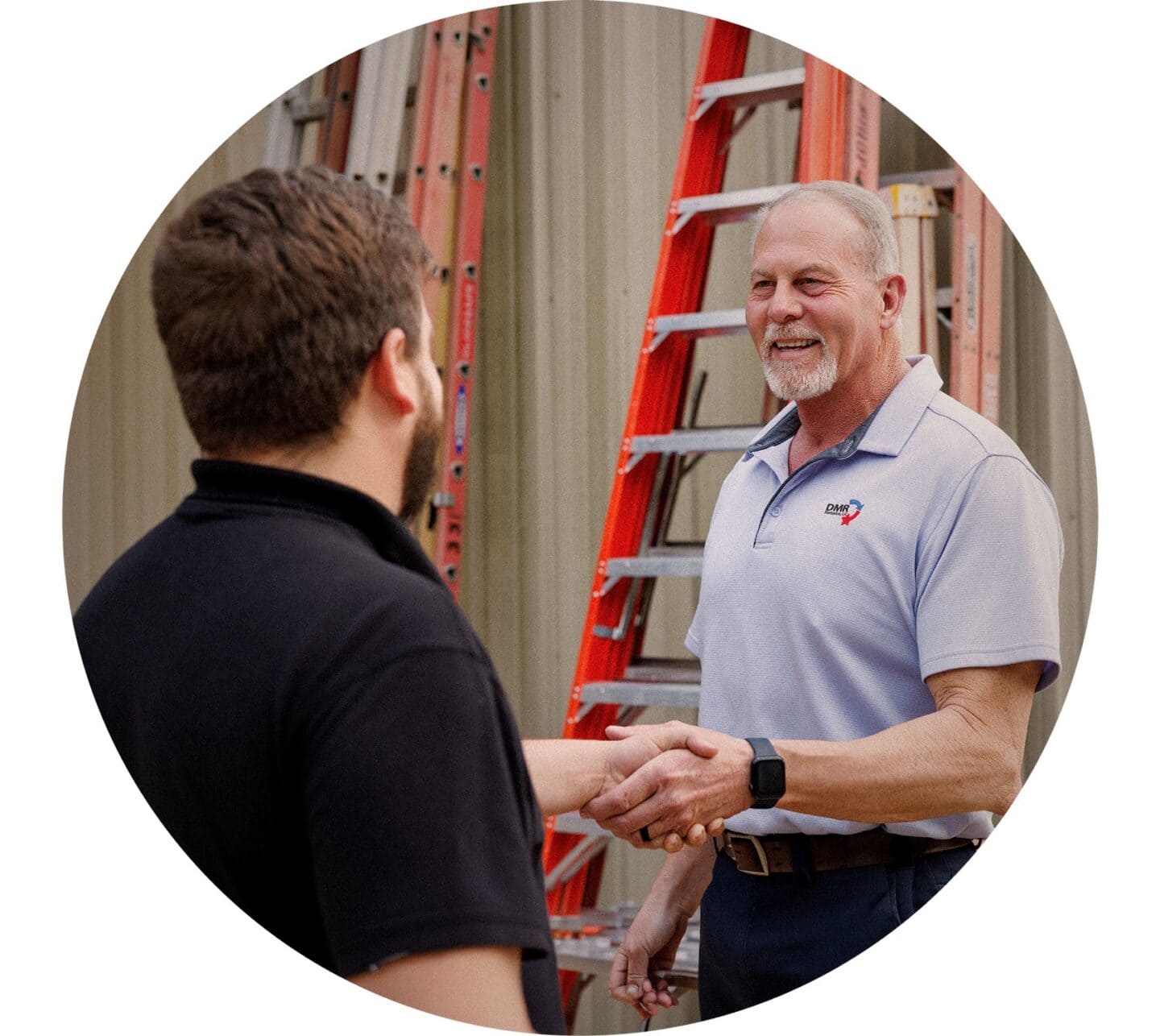 Man at a construction site shaking hands with another man in the foreground.
