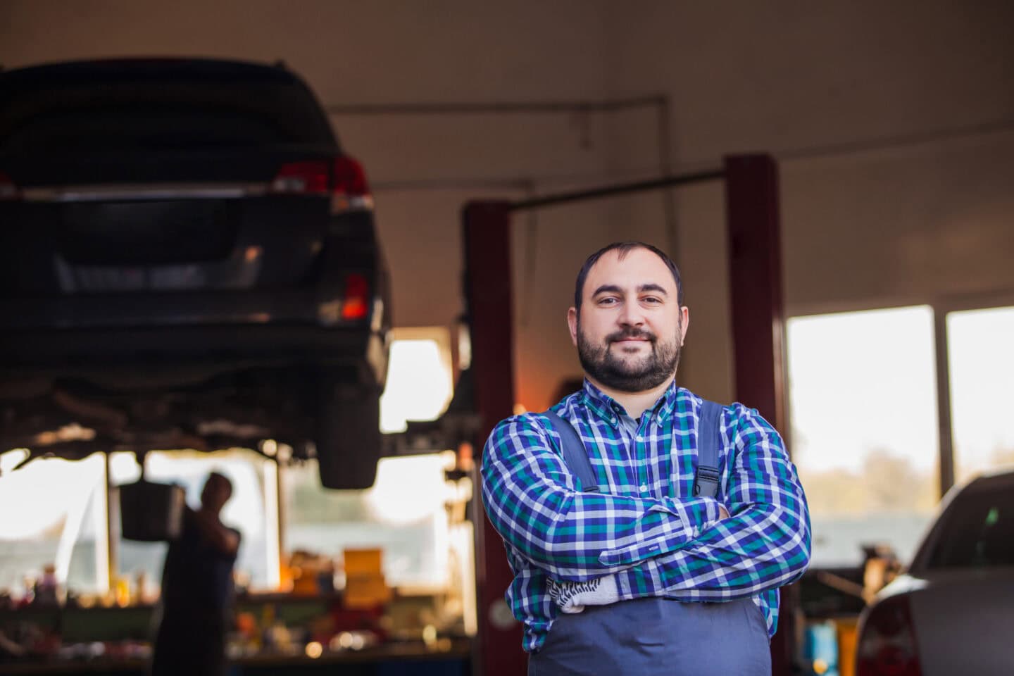 Business owner standing proudly in front of his vehicle maintenance garage